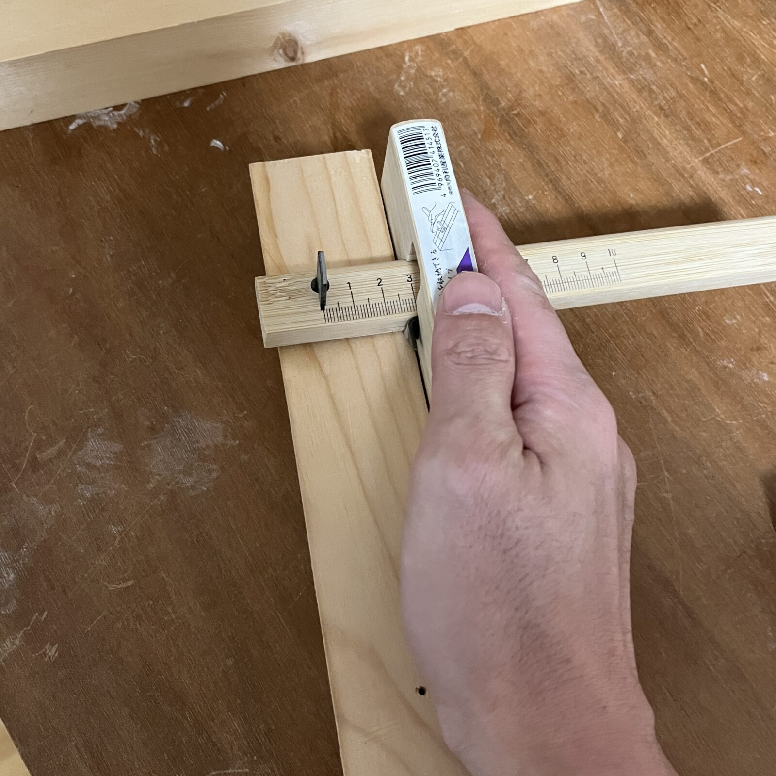 けびきで木材に線を引いている